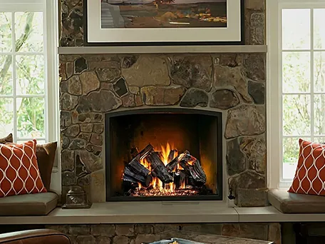 Gas fireplace with realistic log set, installed in a stone fireplace surround.