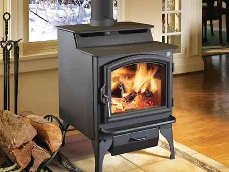 A freestanding wood burning stove with a roaring fire, set on a tile hearth in a cozy living room.
